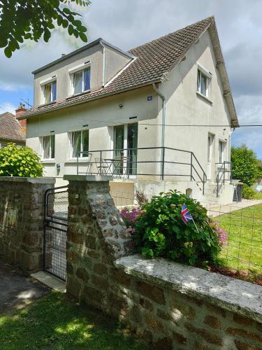 a white house with a fence and some flowers at Le gîte de la tortue in Bayeux