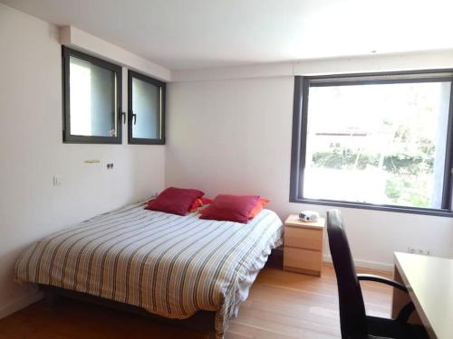 une chambre avec un lit avec deux oreillers rouges dessus dans l'établissement Villa contemporaine proche de Montpellier, à Castelnau-le-Lez