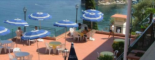 a patio with tables and chairs with umbrellas and the water at Bay Palace Mazzarò in Taormina