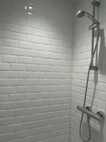 a shower in a bathroom with white tiles at Maison vue baie rénovée 8 couchages in Le Crotoy
