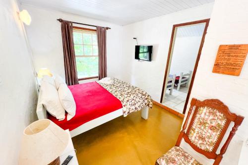 a bedroom with a bed and a mirror and a chair at VELINN Pousada Cesar in Santo Antônio do Pinhal