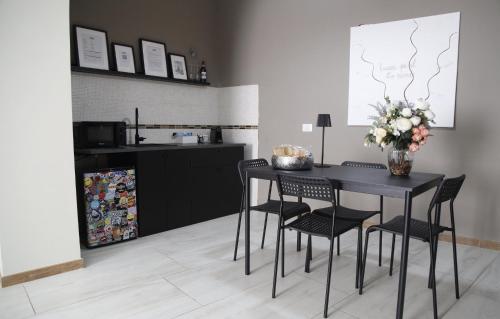 a kitchen with a black table with chairs and flowers at Grey Apartment in Caiazzo
