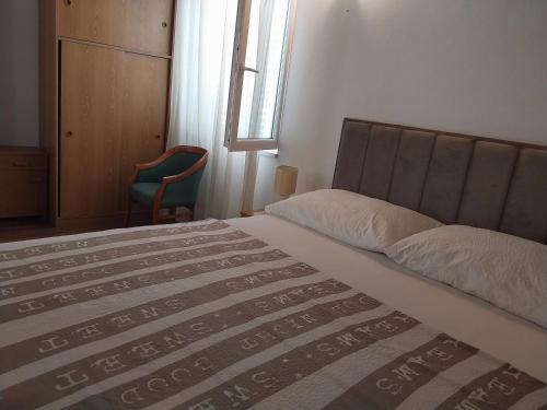 a bedroom with a bed and a chair and a window at Captain's villa in Molunat