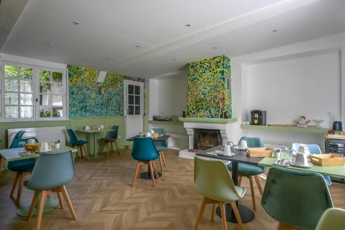 ein Restaurant mit Tischen und Stühlen und einem Kamin in der Unterkunft Le Relais du Beffroi & SPA in Saint-Riquier