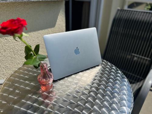 a table with a laptop and a vase with a flower at Hotel Ostseeblick - direkt hinter den Dünen in Ostseebad Karlshagen