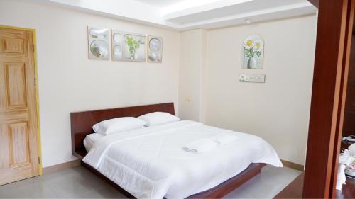 a white bedroom with a bed with white sheets and pillows at Shi-ro-i Poshtel in Hat Yai