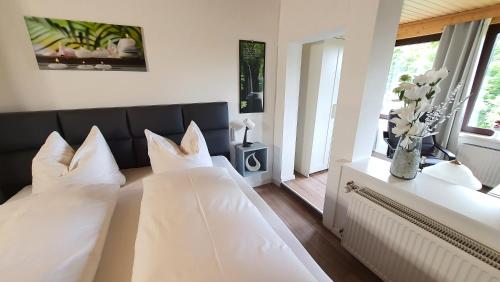 a white bed with white pillows in a room at Hotel Schneiderhof in Braunlage