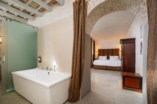 a bathroom with a tub and a bedroom with a bed at Hotel Boutique V in Vejer de la Frontera