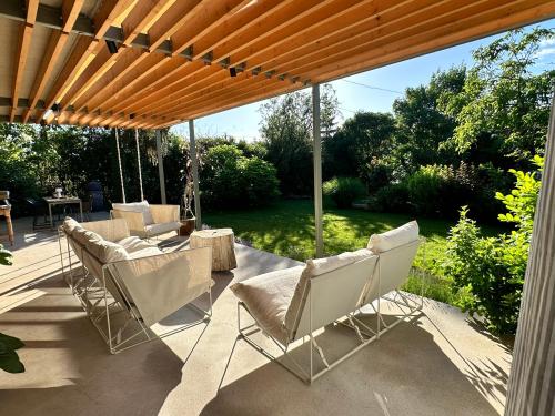 a patio with chairs under a wooden pergola at Hello Balaton in Alsóörs
