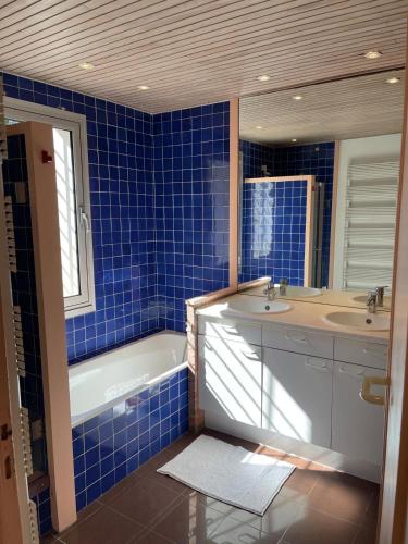 La salle de bains est pourvue de carrelage bleu, d'une baignoire et d'un lavabo. dans l'établissement Belle villa basque familiale, à Arcachon