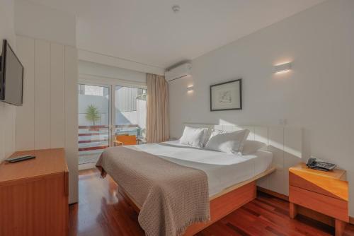 Un dormitorio con una gran cama blanca y una ventana en Costa Nova Hotel, en Costa Nova