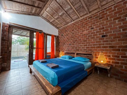 a bedroom with a blue bed in a brick wall at Coconut Dream in Gili Trawangan