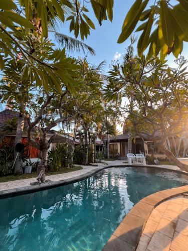 a swimming pool in front of a house with trees at Coconut Dream in Gili Trawangan