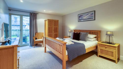 Schlafzimmer mit einem Bett, einem Schreibtisch und einem Balkon in der Unterkunft Mains of Taymouth Country Estate 4* Houses in Kenmore