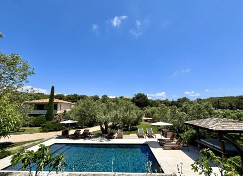 a pool with chairs and umbrellas and a house at Nature & Design in Bonifacio