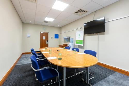 a conference room with a wooden table and blue chairs at Holiday Inn Cardiff City Centre by IHG in Cardiff