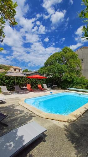une grande piscine avec des chaises et un parasol dans l'établissement Canta aoussel, à Moussoulens