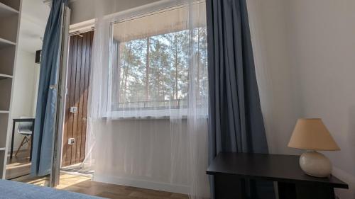 a bedroom with a window and a desk with a lamp at Pine forest house 5 in Gauja