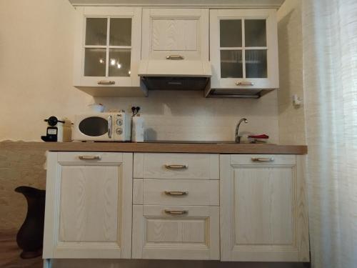 a kitchen with white cabinets and a microwave at Joy's Home in Bari