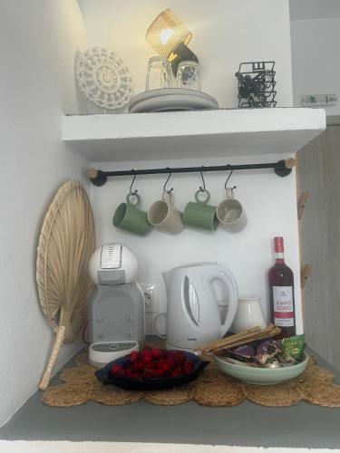 a kitchen with a shelf with cups and a mixer at Akti Rooms And Studios in Livadion