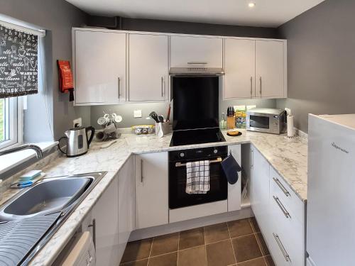 a kitchen with white cabinets and a stove top oven at Racing Retreat in Towcester