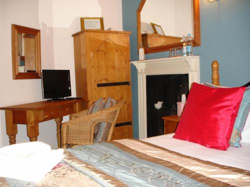 a bedroom with a bed with a red pillow and a desk at The Tollgate Inn in Bradford on Avon