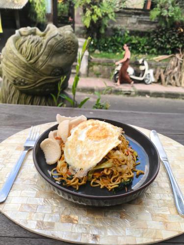 een bord eten met een gebakken ei en spaghetti bij Skyline House Ubud View by EPS in Ubud