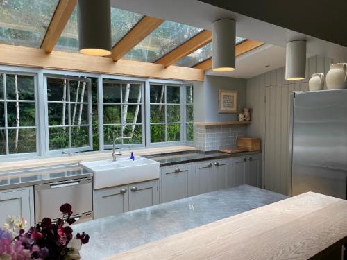 a kitchen with a sink and some windows at Willow Cottage in Studland