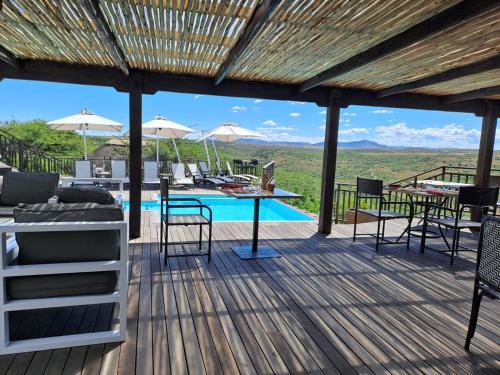 a deck with a table and chairs and a pool at Umzolozolo Private Safari Lodge & Spa in Nambiti Private Game Reserve