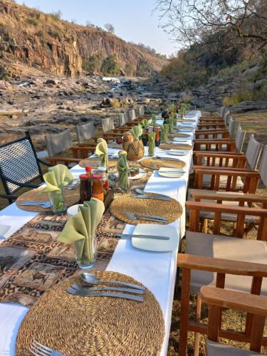 a long line of tables with plates and napkins at Umzolozolo Private Safari Lodge & Spa in Nambiti Private Game Reserve