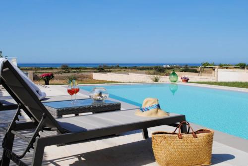 a chair and a table next to a swimming pool at Gold Beach House by LoveSud in Torre Pali 