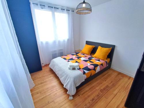 une chambre avec un lit avec des oreillers jaunes et une fenêtre dans l'établissement À 5 min à pied de la gare, du tram et des Rives de l'Orne, à Caen