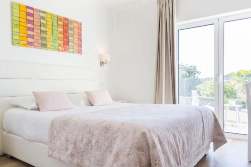 Dormitorio blanco con cama y ventana grande en Boutique Hotel Casa do Outeiro - Arts & Crafts en Batalha