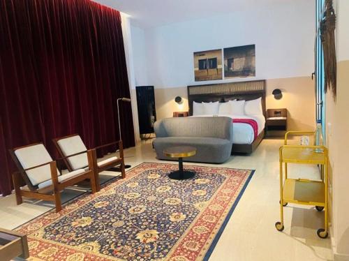 une chambre d'hôtel avec un lit, un canapé et un tapis dans l'établissement Hotel Lepic, à Abidjan