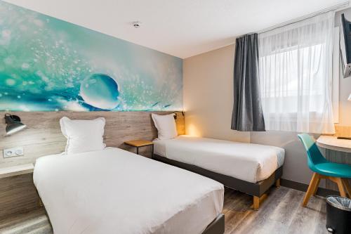 a hotel room with two beds and a desk at Kyriad Direct Tours Sud - Chambray Lès Tours in Chambray-lès-Tours