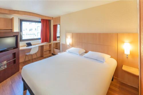 sypialnia z dużym białym łóżkiem i biurkiem w obiekcie ibis Paris 17 Clichy-Batignolles w Paryżu