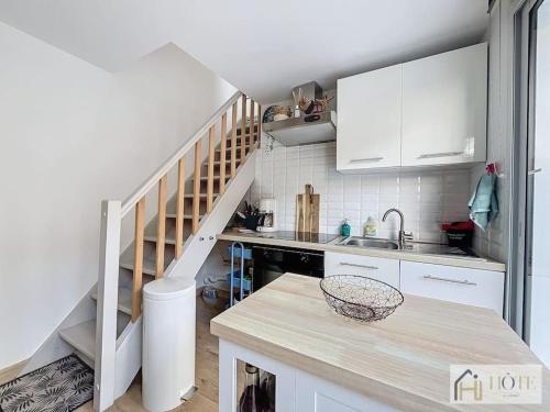 une cuisine avec des placards blancs et un escalier dans l'établissement Havre des Marées - Plage 50m, à Bray-Dunes