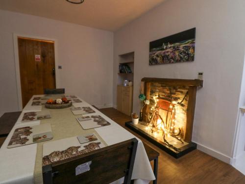 a room with a table with a fireplace in it at Callart View in Ballachulish