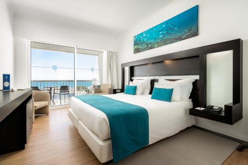 een hotelkamer met een groot bed en een balkon bij Jupiter Algarve Hotel in Portimão
