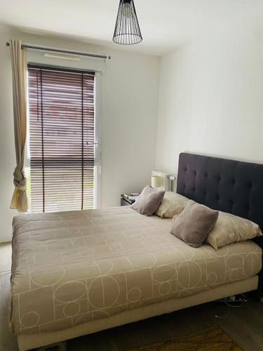 une chambre avec un grand lit avec une grande fenêtre dans l'établissement A cosy 2 bedroom flat, à Villeneuve-la-Garenne