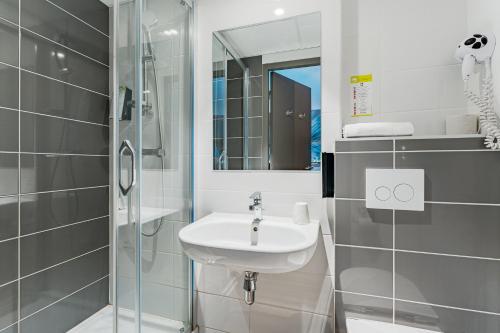 ein weißes Bad mit einem Waschbecken und einer Dusche in der Unterkunft Kyriad Direct Tours Sud - Chambray Lès Tours in Chambray-lès-Tours
