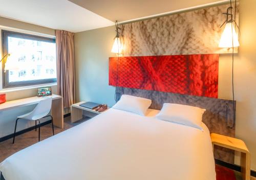 a hotel room with a large white bed and a window at ibis Paris 17 Clichy-Batignolles in Paris