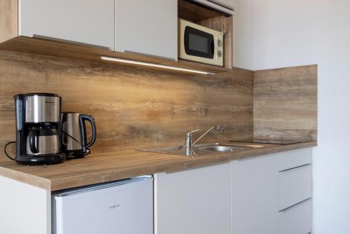 a kitchen counter with a sink and a microwave at Residence Roc E Mare Cargèse in Cargèse