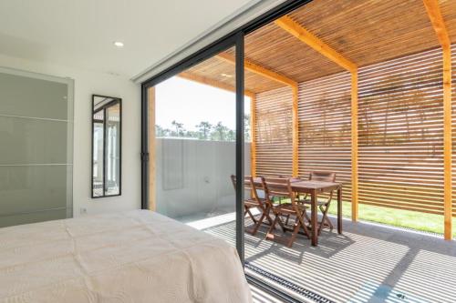 a bedroom with a bed and a table on a balcony at Another Side in Furadouro