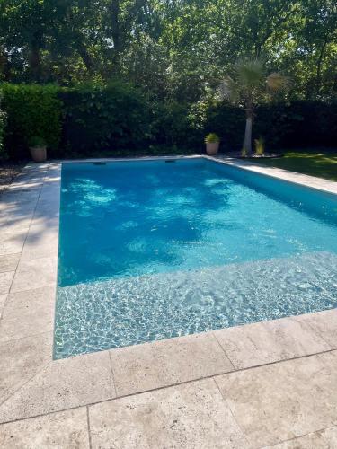 a swimming pool with blue water in a yard at Cabane 14 in Cestas