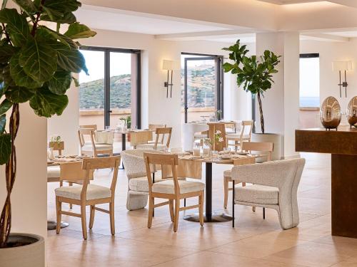 uma sala de jantar com mesas, cadeiras e janelas em Cape Sounio Grecotel Boutique Resort em Sounio