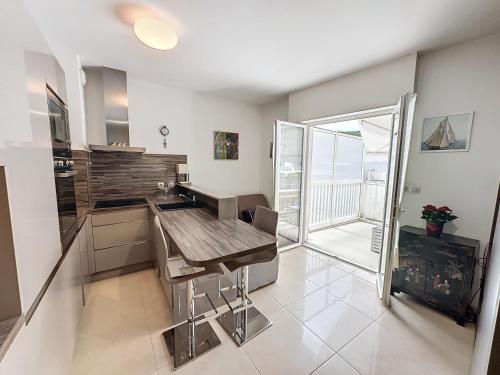 une cuisine avec une table en bois et une grande fenêtre dans l'établissement CAM3 - Beau 2 pièces avec terrasse, à Cannes