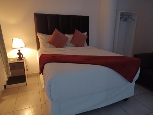 a bedroom with a large bed with white sheets and orange pillows at De Bliss Lodge in Johannesburg