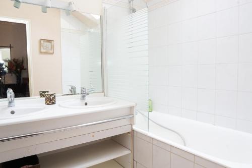 La salle de bains blanche est pourvue d'un lavabo et d'une baignoire. dans l'établissement EXIGEHOME - T3 centre-ville proche de Paris la Défense, Champs Elysée, à Rueil-Malmaison