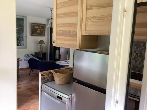 a kitchen with a refrigerator and a dining room at Maison campagne rivière forêt in Le Brévedent